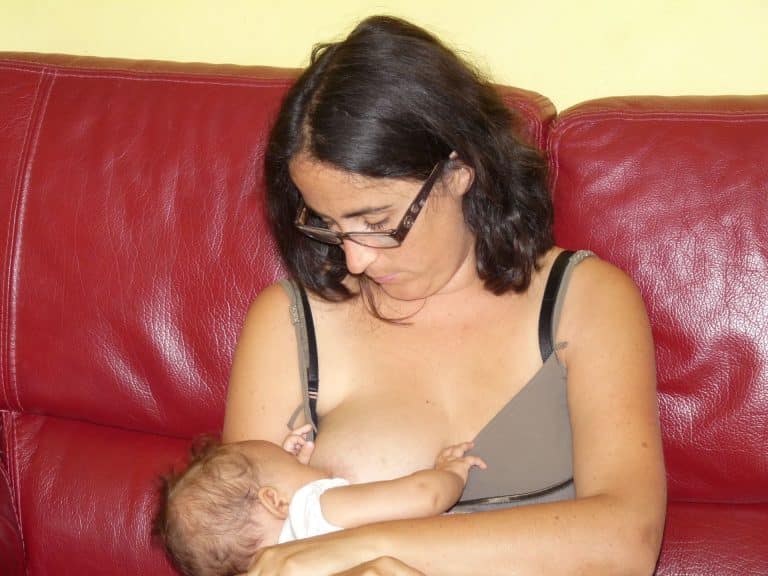 Mère assise dans un canapé qui allaite son bébé